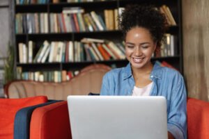 A woman sitting on a couch, focused on her laptop, representing the unique features of CIPD assignment help.